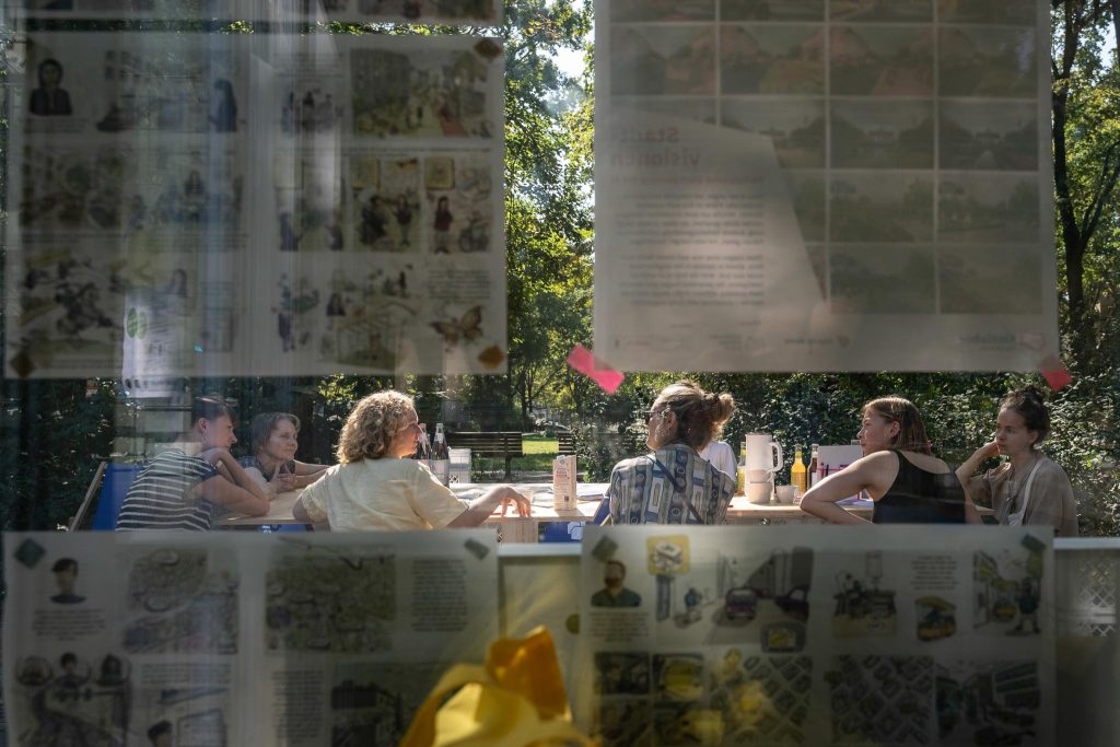 Eine Gruppe von Menschen an einem Tisch ist durch eine Glasscheibe zu sehen.