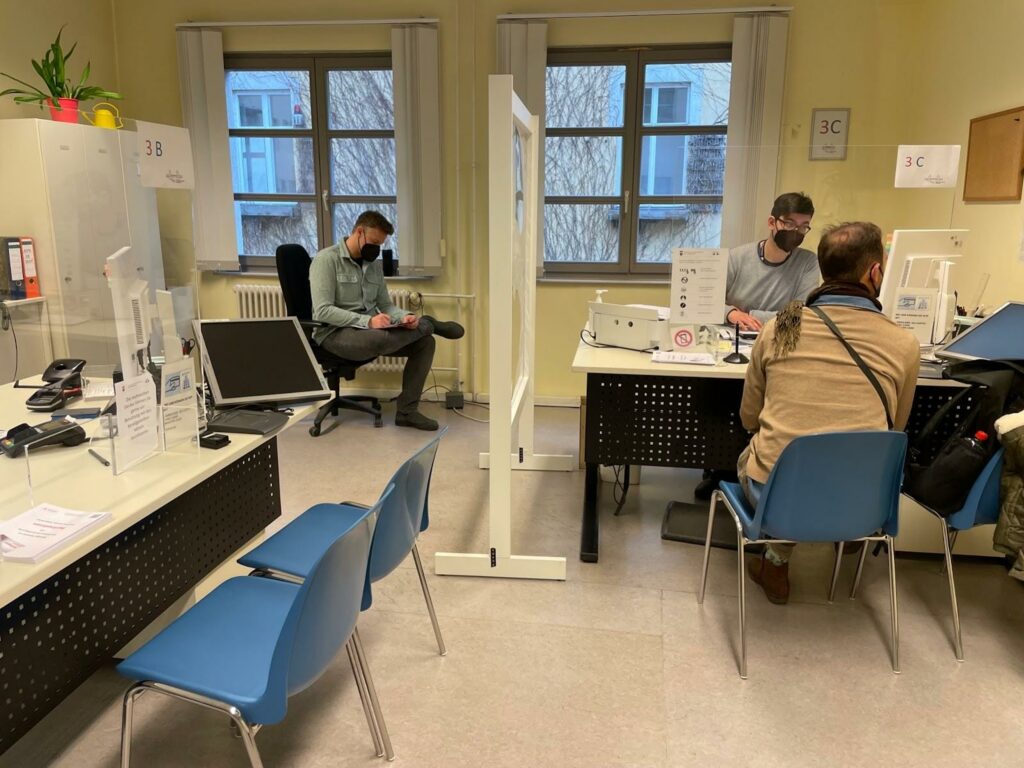 Im Ausbildungsamt Friedrichshain-Kreuzberg. Ein Mitarbeiter des CityLAB Berlin beobachtet einen Mitarbeiter des Ausbildungsamtes in Interaktion mit einem Gast und macht sich Notizen. 