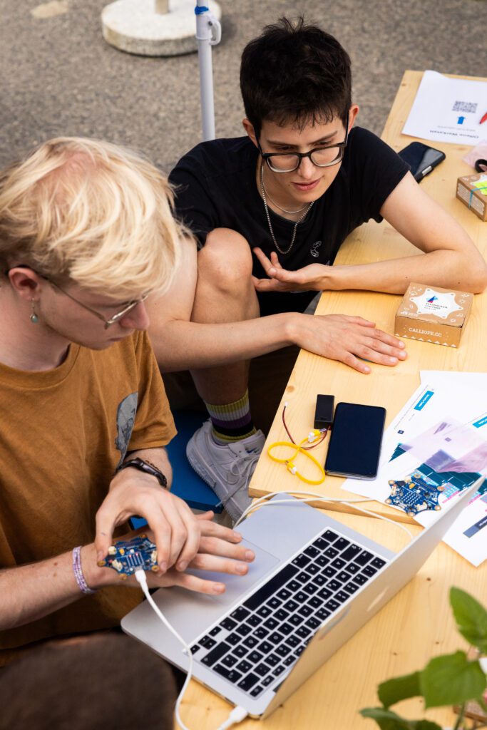 Zwei Menschen arbeiten an einem Tisch mit einem Laptop an einem Arduino.