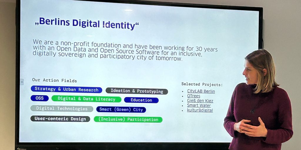 Julia Zimmermann spricht vor einem Monitor mit der Folie "Berlins Digital Identity"