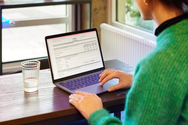 Eine Frau, die ein Formular an einem Laptop ausfüllt.