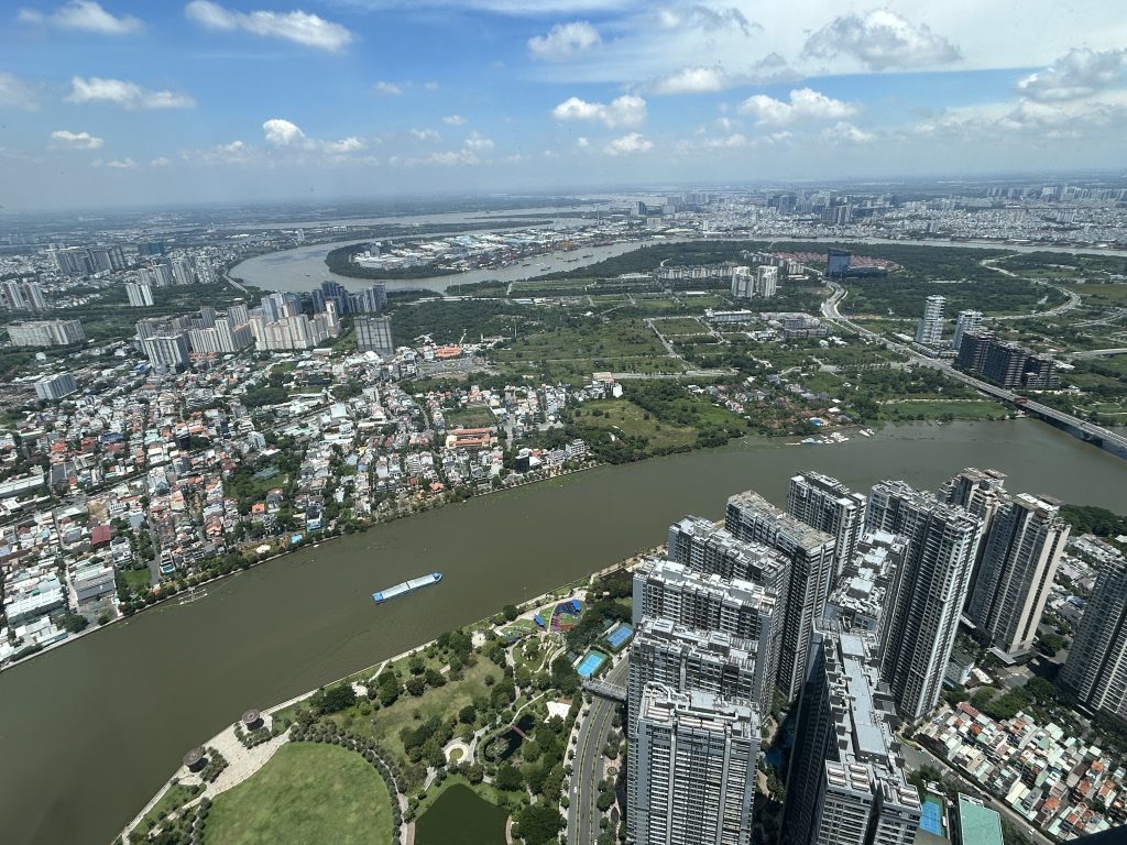 Aussicht von oben auf Vietnams Hauptstadt mit Flussverlauf, Gebäuden und viel Grün