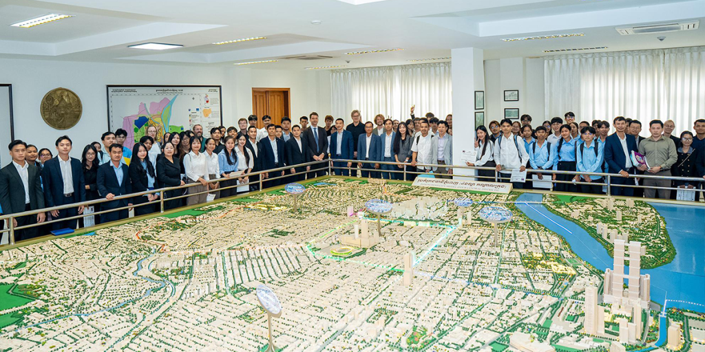 Gruppenfoto des Build4People Projekts mit Projektpartnern in Kambodscha und dem CityLAB vor einer großen Karte des Smart City Bauvorhabens 
