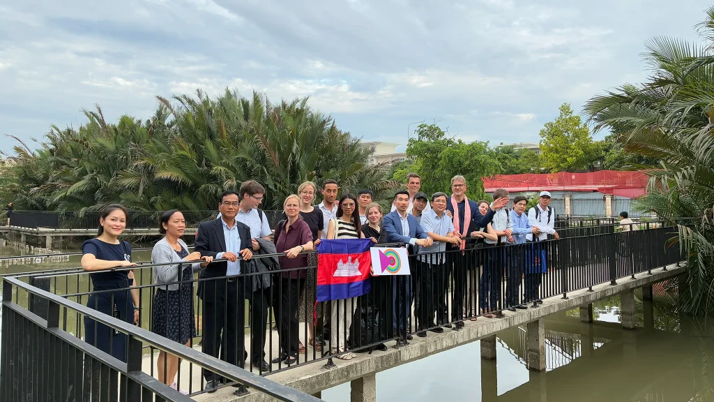 Gruppe auf einer Brücke über Wasserflächen und mit Palmen im Hintergrund